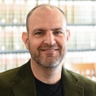 Man sitting inside a library, smiling. 