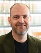 Man sitting inside a library, smiling. 