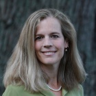 woman smiling, standing outside wearing green top. 