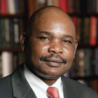 man smiling, standing in an office with bookshelves holding many books.