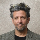 Portrait photo of Taussig-Rubbo standing in front of a concrete wall. 