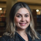 Woman smiling, standing inside a library. 