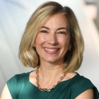 woman in green dress, outside next to a building.