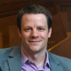 man sitting on courtroom bench, smiling. 