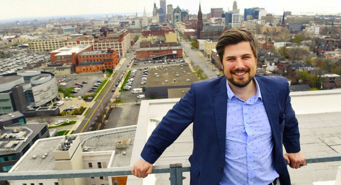Matthew Pekley poses outside with Buffalo's cityscape in the background.