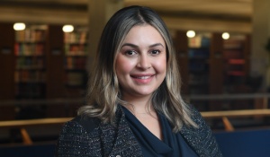 woman smiling, standing in a library. 