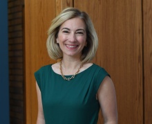 woman standing, smiling.