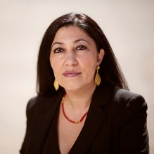 woman wearing black jacket, red necklace. 