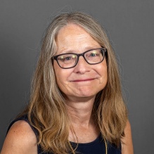 Woman wearing glasses, smiling. 