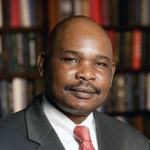 Man standing in front of a bookcase, smiling. 