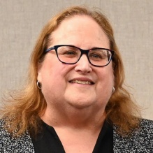 Woman wearing glasses, smiling. 