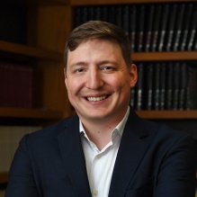 Man standing in front of several bookcases, smiling. 