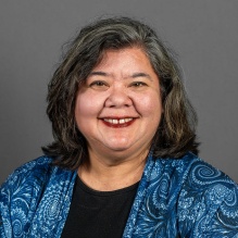 Woman wearing a blue jacket, smiling. 