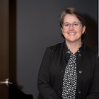 Woman wearing glasses, standing in a doorway. 