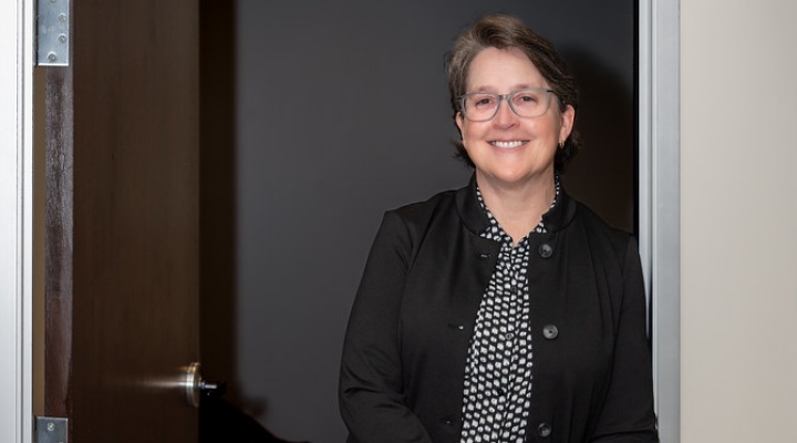 Woman wearing glasses, standing in a doorway. 