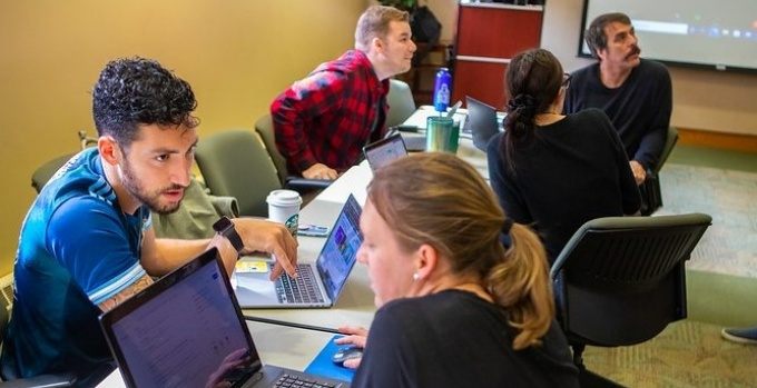 UB Law clinic students working on laptops at a table.