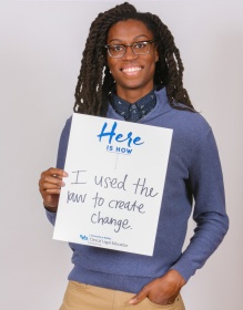 UB Law clinic student holding a sign that says Here is how I used the law to create change.
