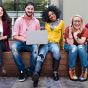 photo of a diverse group of students sitting next to each other and smiling. 