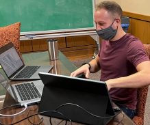 Law student Stephen Soos surrounded by laptop computers on a desk.
