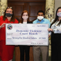 students and clinic faculty holding up a giant check. 