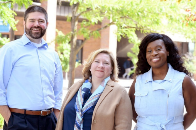 a man and two women standing outside, smiling.