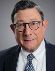 portrait of a man wearing a tie and glasses.