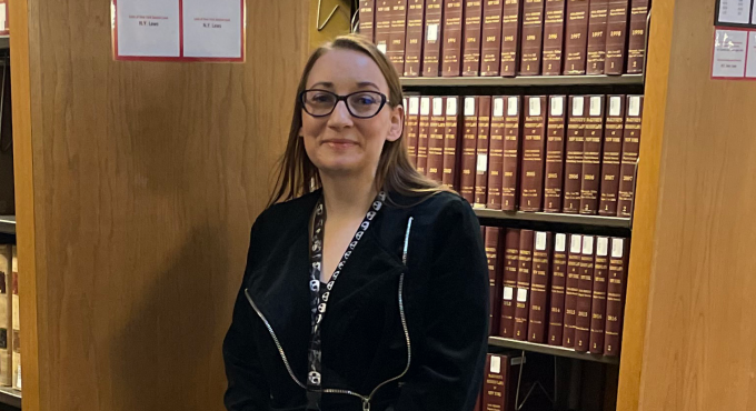 woman standing next to a bookshelf.