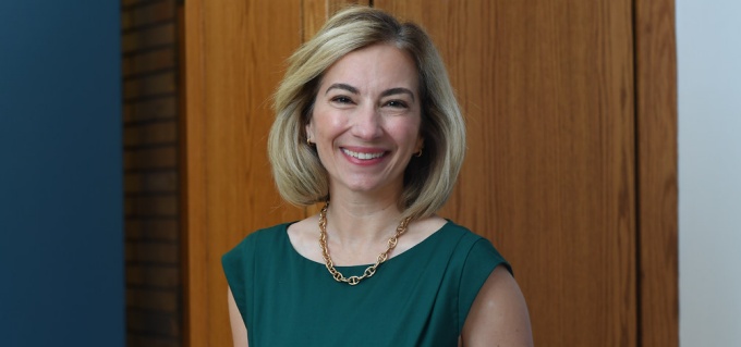 woman standing inside, smiling, wearing green dress.