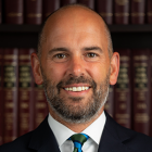 a man standing in front of a bookcase containing legal books.