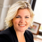 woman wearing pearl necklace, smiling.