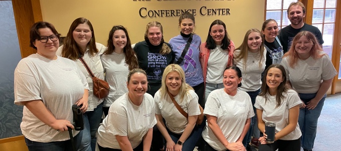 young adults wearing plain white t-shirts posing for a group photo.