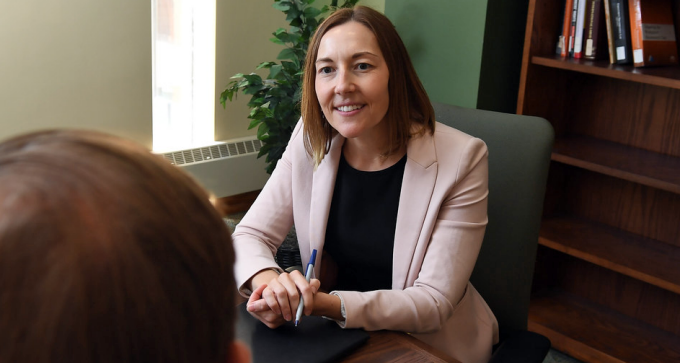 Woman wearing blazer talking to a student.