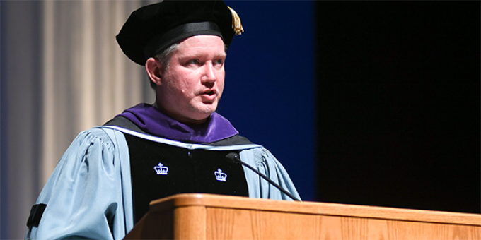 man speaking at a graduation podium.