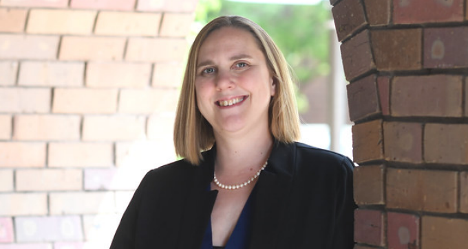 woman standing outside in front of a brick wall.