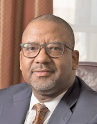 man sitting in leather office chair in front of a window with curtains.