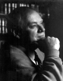 black and white photo of Joyce, profile view, bookshelf behind him.