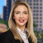 a young woman standing in front of a city background, smiling.
