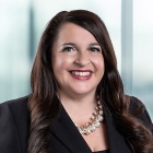 smiling woman standing in front of a large window.