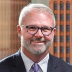 man wearing glasses, smiling.