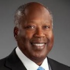 man wearing blue tie, smiling.