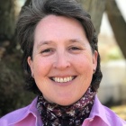 woman standing in front of tree outside, smiling.