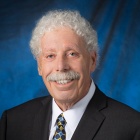 man wearing suite, tie, smiling. 