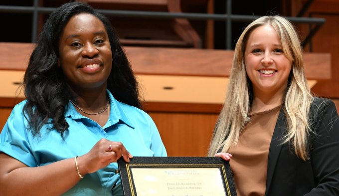 two women on stage, one holding an award. 