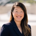 woman standing outside, smiling. 