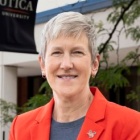 woman standing outside, wearing red jacket, smiling. 