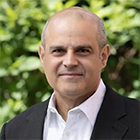 man wearing businesss suit, standing outside, smiling. 