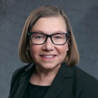 woman wearing businesss suit, smiling. 