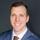 man wearing suit and tie, smiling. 