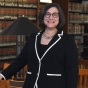 woman smiling standing inside a library. 