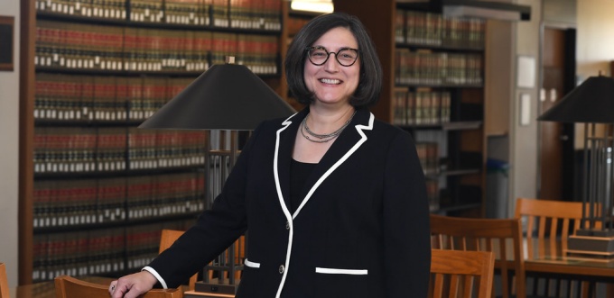 woman smiling standing inside a library. 